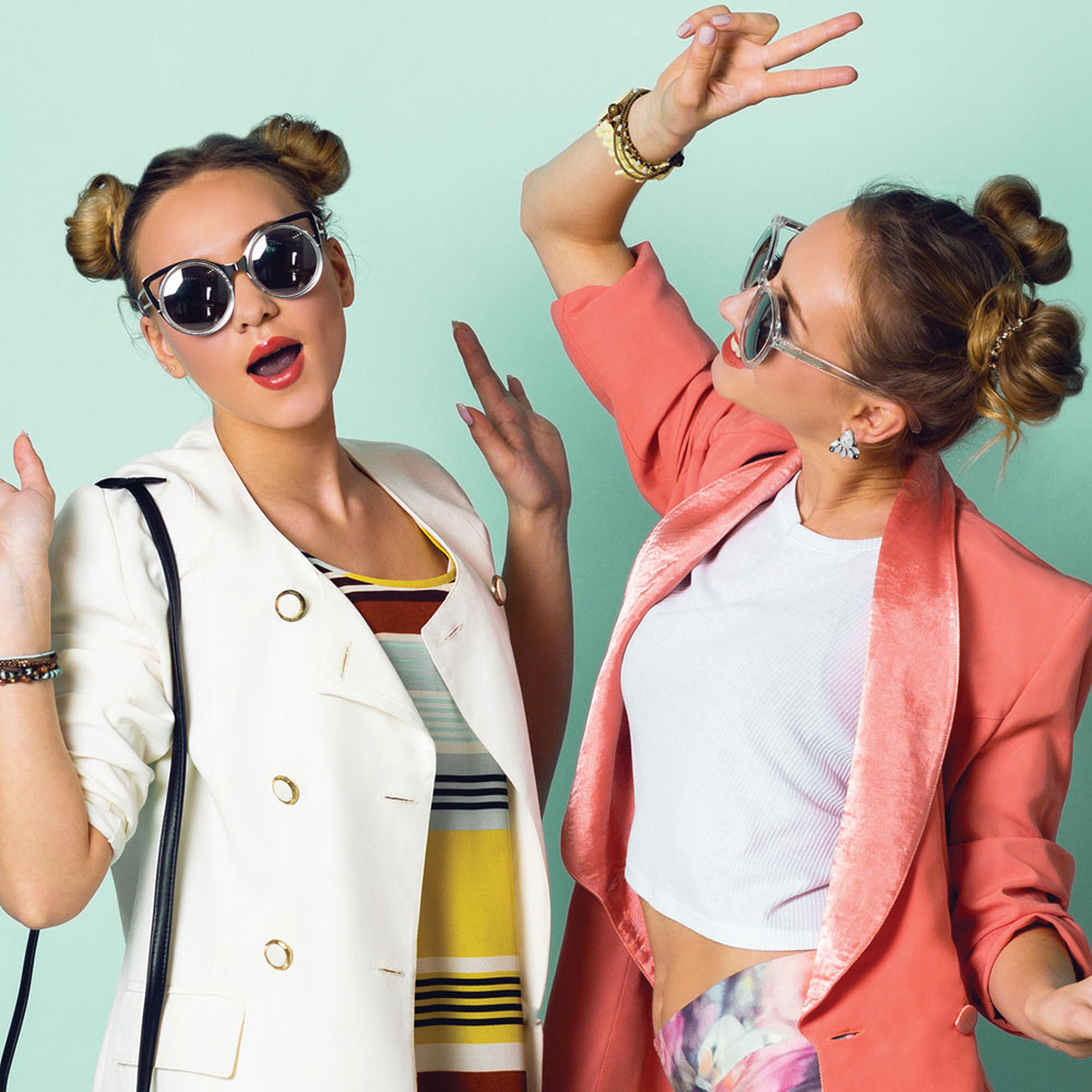 Two young women in sunglasses and rolled up pigtails acting silly