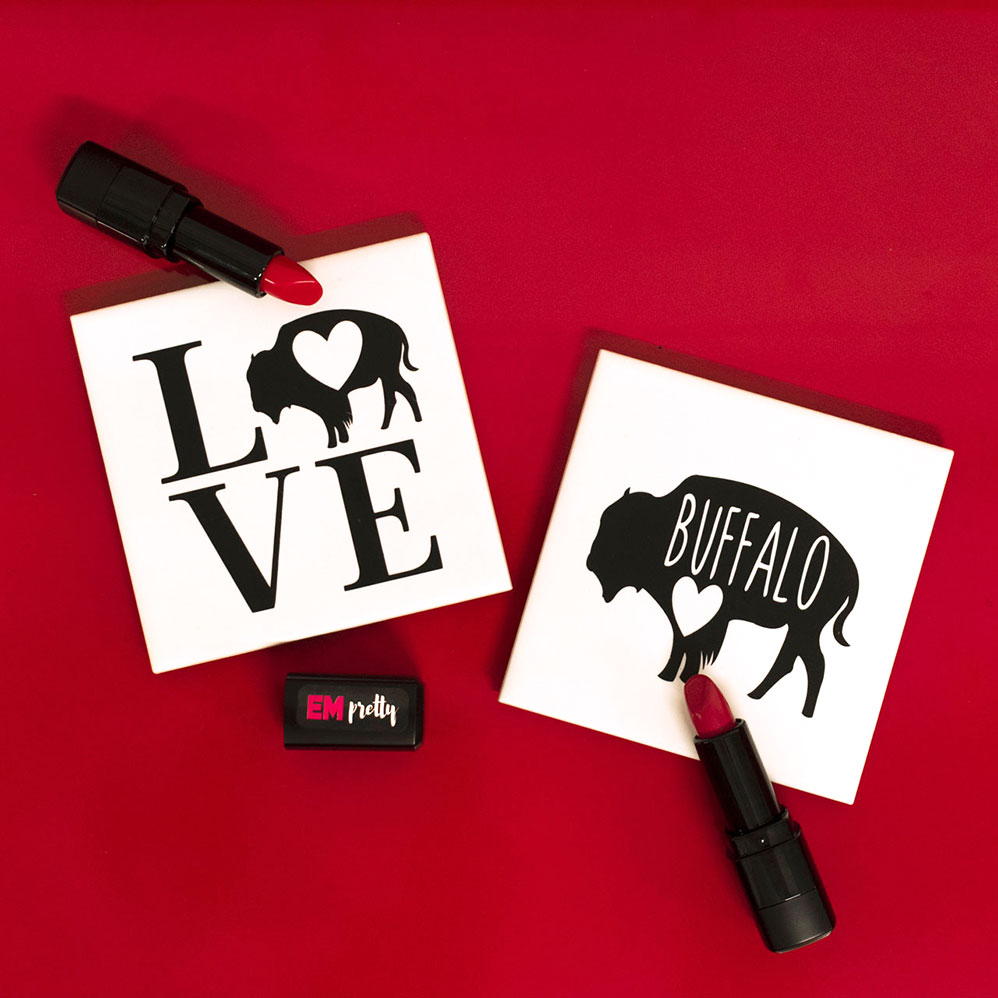 Two white coasters that say Love Buffalo on red background with two red lipsticks