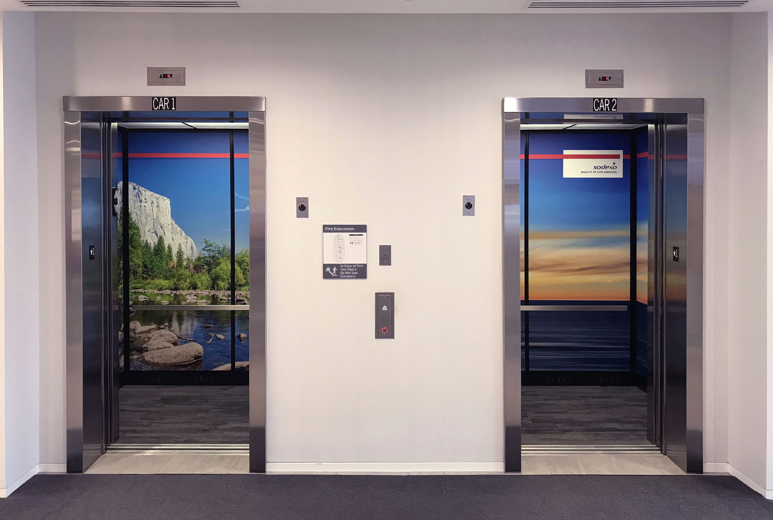 Two open elevators one with full scale photo of Yosemite and the other with a full scale photo of the sunset over the ocean