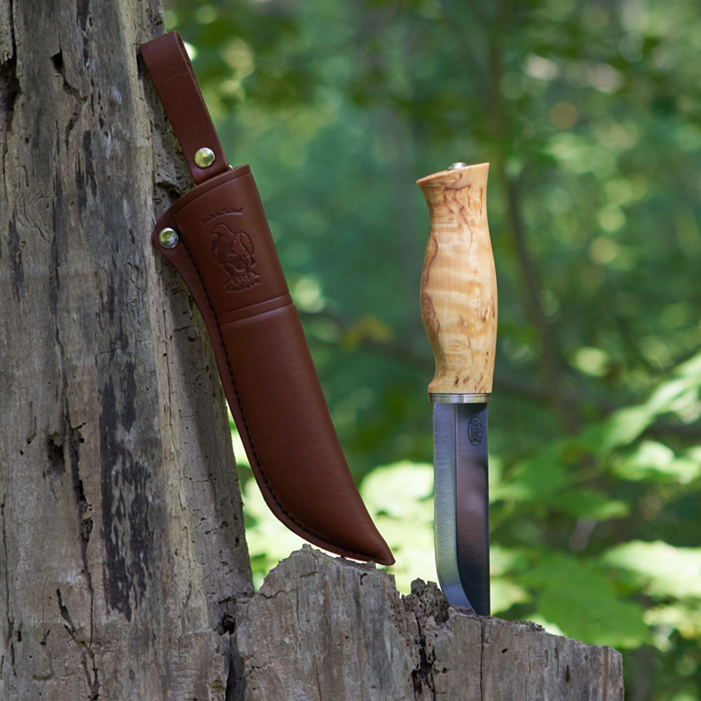 Scandinavian knife stuck into dead tree trunk with leather sheath